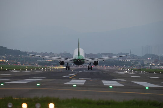 A commercial jet aircraft lands on the runway at dusk.