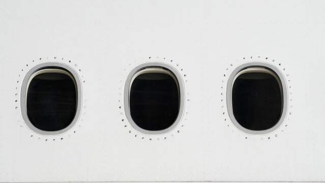 Detailed view of aircraft windows on a white fuselage side of passenger airplane for travel and aviation concept background showing clean metal surface and rivets