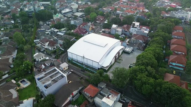 Wide aerial pullback revealing curved structure and suburban sprawl