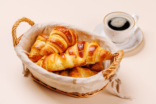 Aromatic croissants in wicker basket with cup of coffee