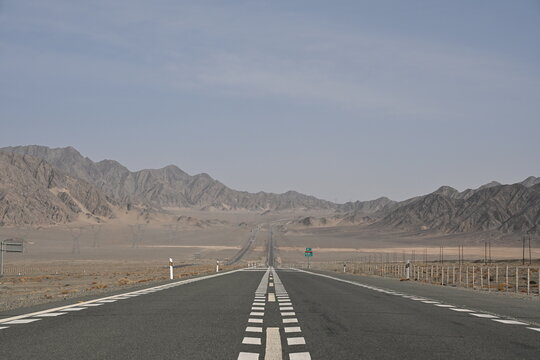 G30 Highway cuts through Gansu's rugged landscapes like a concrete ribbon, weaving between arid mountains and vast deserts under endless blue skies.