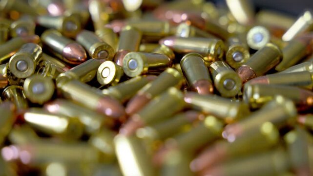 Pile of 9mm bullets rotating clockwise in circular formation. Close up of ammunition cartridges spinning with metallic shine