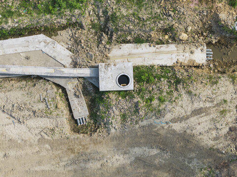 Aerial view of new town infrastructure with concrete drainage systems, manholes, and underground pipes at a construction site with dirt and tire tracks in Taiwan.