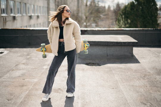 Stylish Woman with Skateboard on Rooftop
