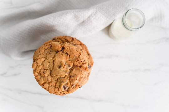 Stack of homemade chocolate chip cookies next to a vintage glass
