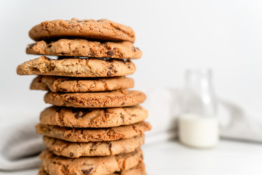 Stack of homemade chocolate chip cookies next to a vintage glass