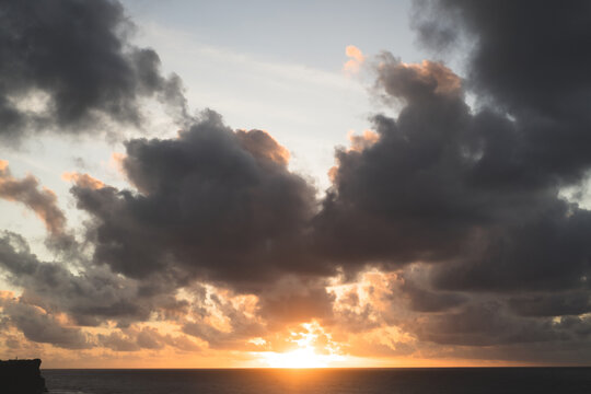 Dramatic sunset with sun breaking through dark storm clouds, Bali