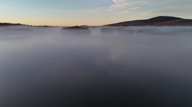Low fog hangs over a beautiful lake in Maine at sunrise.