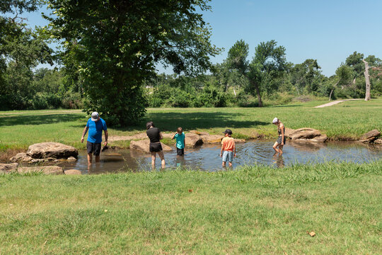 Father and  children wading and playing in shallow creek outdoors