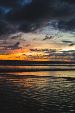 Vivid sunset reflected in ocean waves at Canggu beach, Bali