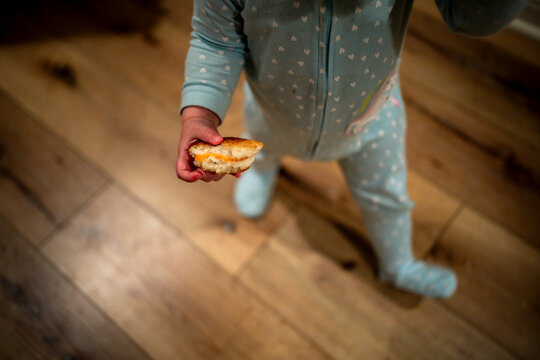 Toddler Holding Half Eaten Cheese Sandwich in Pajamas