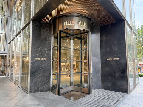 Shanghai, China - November 24, 2025: Miu Miu Boutique Entrance with Revolving Door and Bronze Canopy