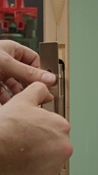 Close-up shot of a craftsman inserting a mortise lock mechanism into a
precisely cut slot in a wooden door. The scene highlights detailed woodworking
craftsmanship and careful alignment.