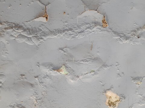 Close-up view of cracked, textured wall with spalled sections on a wall surface. Cracked wall with severe bubbling and peeling due to moisture.