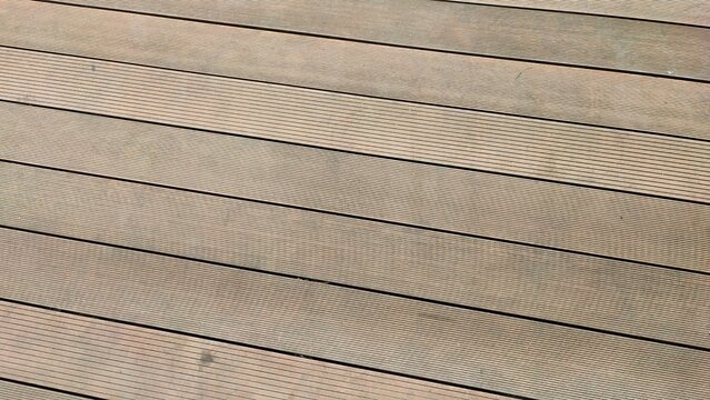 A textured construction featuring a weathered wooden plank panel set against a rough concrete block wall background with natural brown timber material.