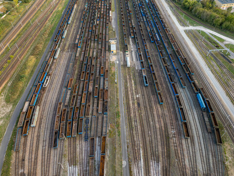 Aerial view of numerous freight wagons and cargo trains parked on multiple tracks at a large railway yard in Warsaw, Masovian Voivodeship, Poland.