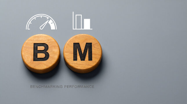 Natural wood discs spelling BM with a speedometer and comparison bar chart above on a cool grey background for business benchmarking.