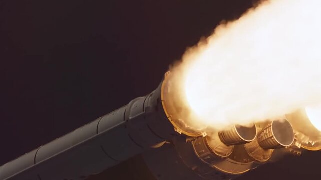 Powerful rocket engine nozzles firing bright plumes of fire and smoke during a night time space mission launch.