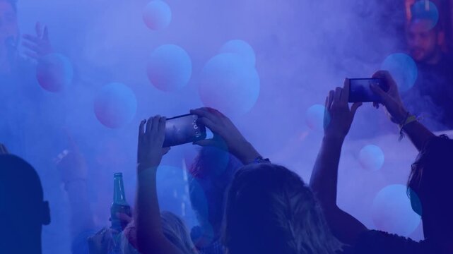 Crowd raising phones, recording as performer starting song, bokeh overlays and fog capturing music