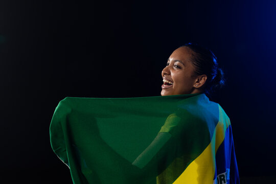 African American woman looking over shoulder smiling, wearing flag in blue-rim studio, copy space