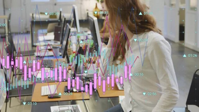 Woman taking call and handling papers while analyzing finance charts overlaying workstation