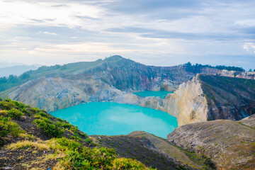 Obraz premium Stunning turquoise volcanic lake of Kelimutu under a cloudy sky, iconic travel destination in Flores