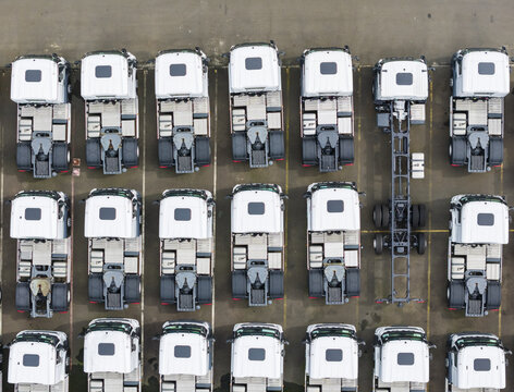 Aerial view of rows of new white semi-truck cabs parked in a manufacturing facility lot with organized alignment on asphalt Taiwan.