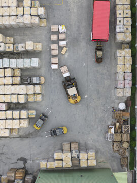 Aerial view of forklifts moving wooden crates and pallets near a red shipping container in an industrial yard Taiwan.