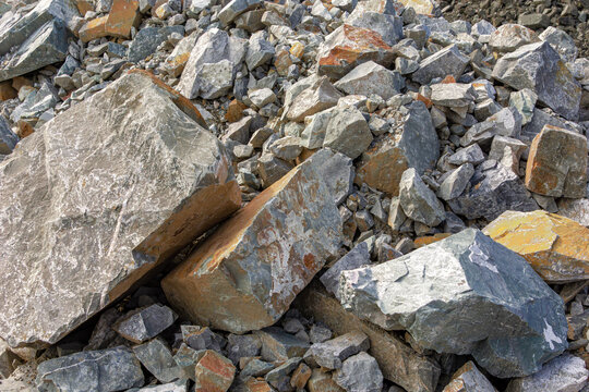 Close up view of large rough boulders and crushed stone piled at outdoor construction material storage site