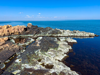 Fototapeta premium Rocky shoreline with calm water and clear skies near a coastal area during the day