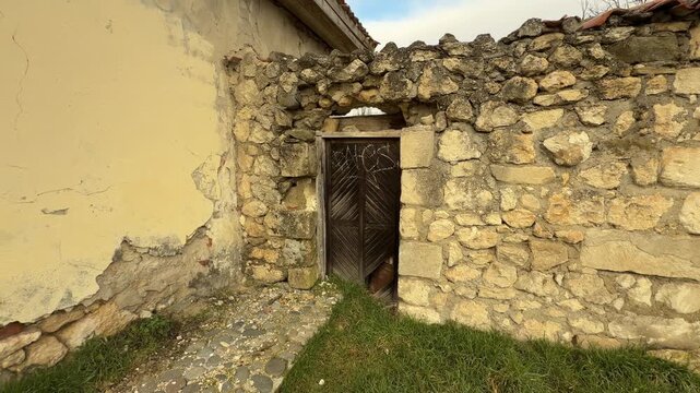 An old wooden door stands tucked inside a rough, broken stone wall. The peeling paint and messy rocks create a lonely, mysterious feeling. This quiet scene tells a story of a place forgotten by time.