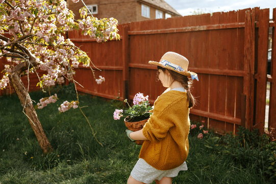 Girl walking with flowers near blooming tree in backyard