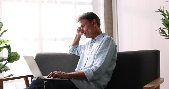 Portrait of happy arab freelancer man sitting at desk with laptop computer at home office, looking and smiling at screen
