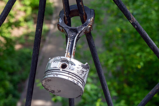 An engine piston hangs on an iron fence: a symbol of love to vehicles