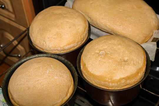 A high-angle shot of a batch of freshly baked, golden-brown yeast buns cooling on a baking tray. The soft, fluffy texture and rustic appearance of the bread rolls evoke a cozy home-baking atmosphere. 