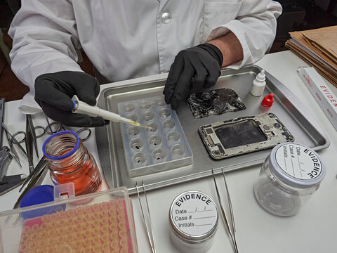 Scientific police extract pieces of burnt smartphone involved in lab murder, concept image