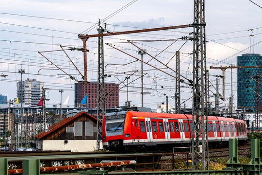 Commuter transit train runs on railway tracks beneath cables through urban Frankfurt Germany highlighting transportation for everyday travel