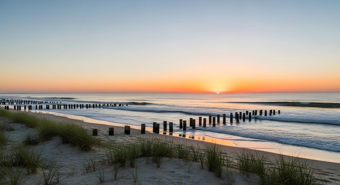 Serene beach sunset golden hour over the ocean with wooden groynes