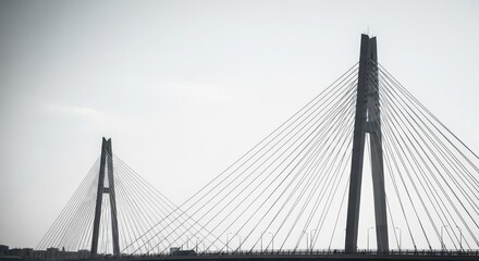 Obraz premium Striking modern cable-stayed bridge with geometric design and towering supports against a bright sky