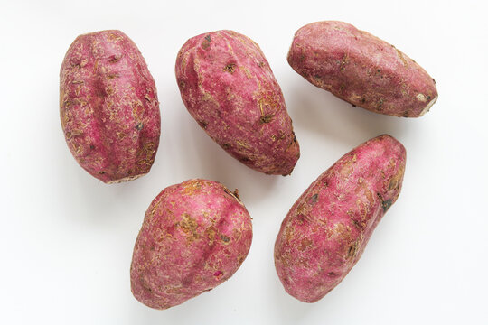 Five raw sweet potatoes, isolated on a clean white background.