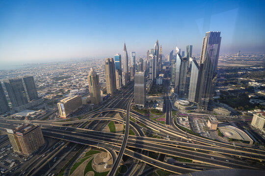 Aerial view of Sheikh Zayed Road skyline with modern skyscrapers and complex highway interchanges under a clear blue sky Dubai, Dubai, United Arab Emirates.