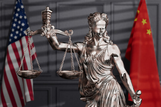 International Justice And Trade Conflict. Femida Statue With Scales Between American And Chinese Flags In Blurred Courtroom Interior. 3d Rendering