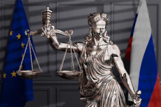 International Justice And Sanctions Dispute. Femida Statue With Scales Between European Union And Russian Flags In Blurred Courtroom Interior. 3D Rendering