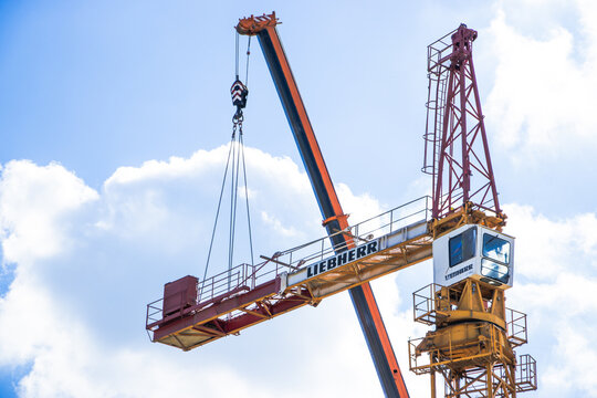 Poznan, Polska - April 23, 2026: Liebherr crane with a long arm hoisting a load against a bright blue sky