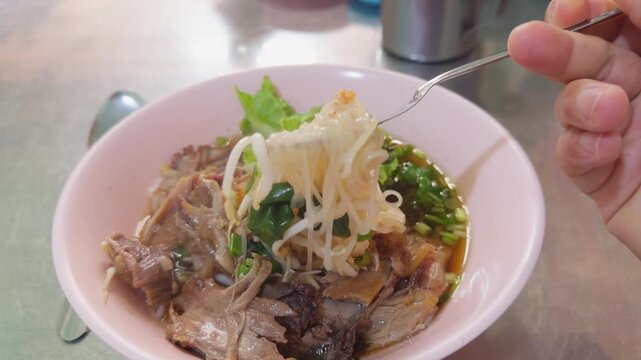 Thai Pork Leg Noodle Soup with Fork Lifting Noodles from Pink Bowl