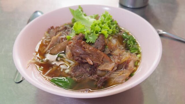 Thai Pork Leg Noodle Soup Served in Pink Bowl, Slow Pan Shot