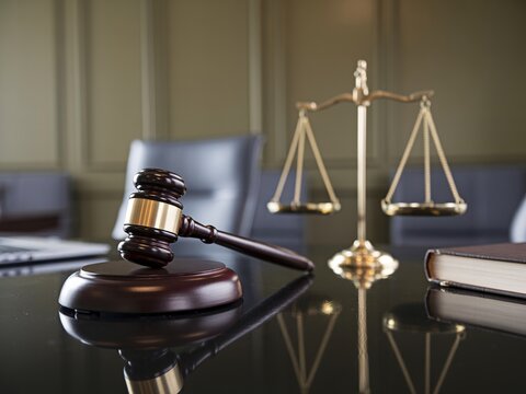 Gavel and scales of justice on reflective desk in office