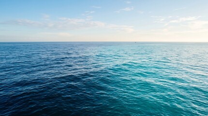 Fototapeta premium Sea surface extends to the distant horizon under a pale morning sky, showcasing the vast and tranquil nature of the deep blue water that provides a sense of peace and endless space for travel.