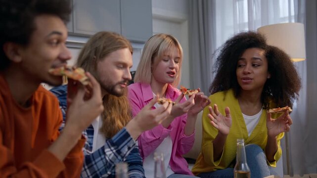 Carefree multiethnic friends four people men women talking at home party eating pizza food delivery African Caucasian girls and guys enjoying slices diversity friendship indoors unhealthy nutrition