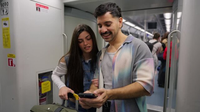 Young tourist couple using smartphone on subway train